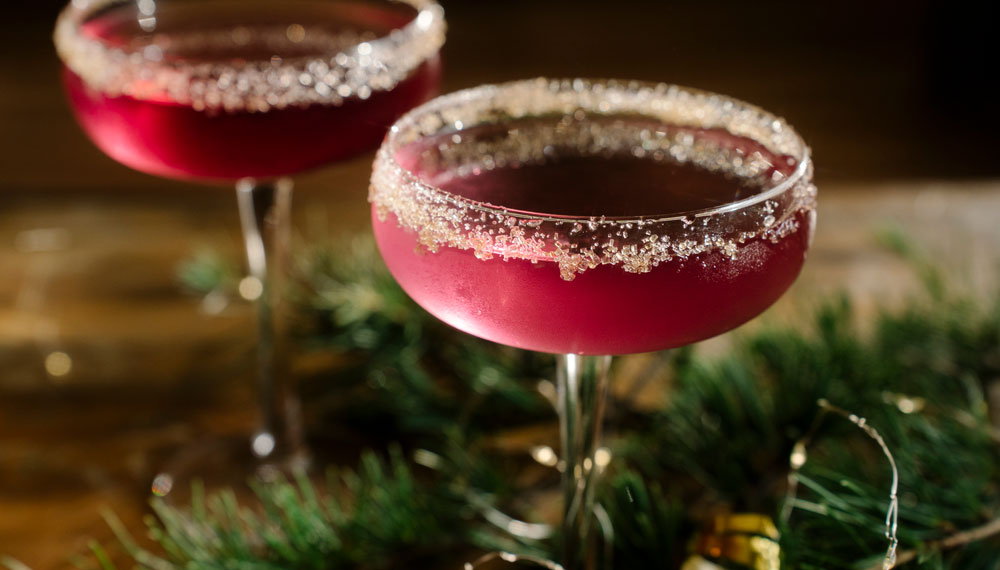 Two red holiday cocktail in sugar-rimmed glasses
